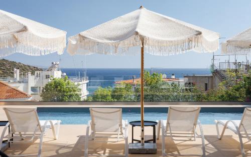 un patio con sedie bianche, ombrellone e piscina di Villa Nefeli Athenian Riviera ad Anávissos