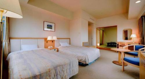 a hotel room with two beds and a desk at Grand Hotel New Oji in Tomakomai