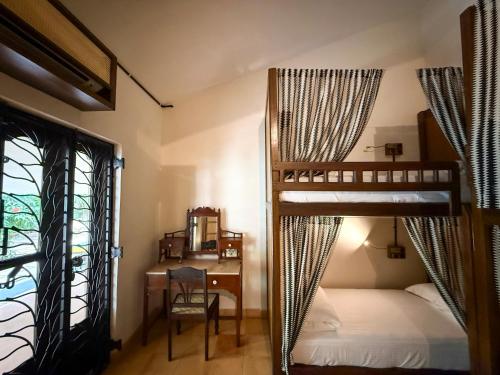 a bedroom with two bunk beds and a desk and a window at Malkin Hostel in Arpora