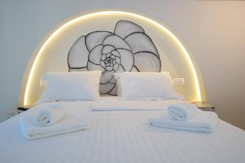 a bed with two towels on it with a painting on it at Maroussa Studios in Agia Anna Naxos