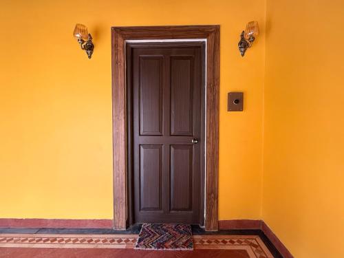 a door in a room with an orange wall at Malkin Hostel in Arpora