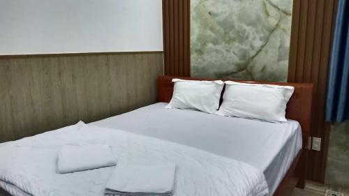 a bedroom with a bed with white sheets and pillows at Hoàng Yến Hotel Mỹ Tho in My Tho