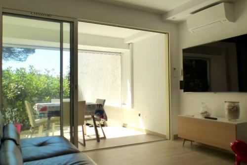 d'un salon avec une porte coulissante en verre s'ouvrant sur une terrasse. dans l'établissement Apartment with garden 200 m from the beach, à Sanary-sur-Mer