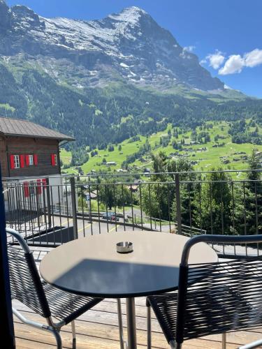 a table and chairs on a balcony with a mountain at Jungfrau Lodge, Swiss Mountain Hotel in Grindelwald