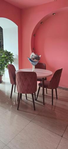 a table and chairs in a room with pink walls at Sanapiro + in Tbilisi City