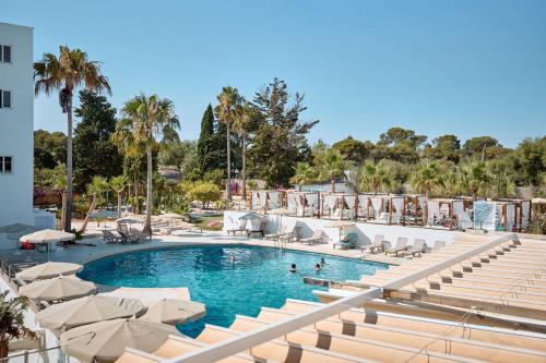 a swimming pool with chairs and umbrellas at a resort at Hotel Ankaa - Adults Only in Porto Cristo