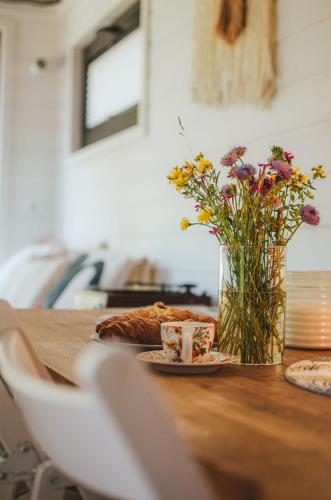 a table with a plate of food and a vase of flowers at Heaven Reset Spa Luksusowy Glamping Jacuzzi w Naturze Blisko Warszawy in Korczew