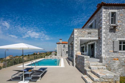 a stone house with a swimming pool and an umbrella at Asanti Villas in Lévktron