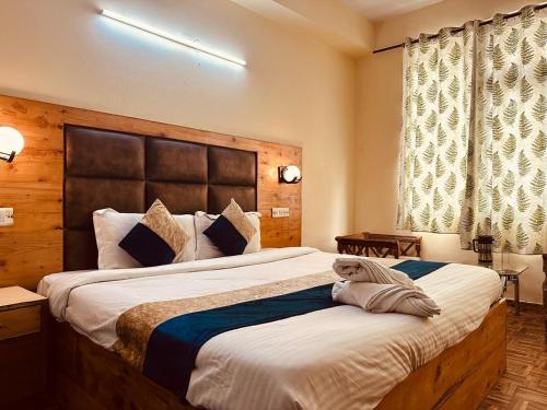 a bedroom with a large bed with a large headboard at Antriksh cottage Manali in Manāli