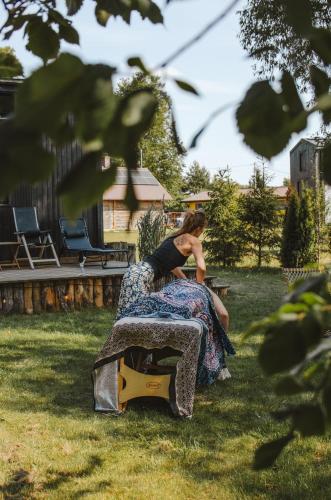 a woman sitting on a bench in the grass at Heaven Reset Spa Luksusowy Glamping Jacuzzi w Naturze Blisko Warszawy in Korczew