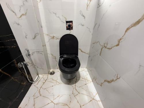 a bathroom with a black toilet and marble walls at Hotel Shree Sumedh in Navi Mumbai