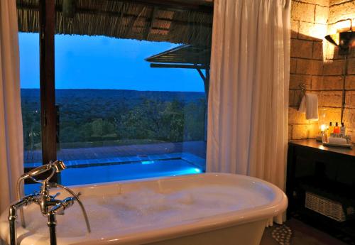a bath tub in a bathroom with a large window at Zwahili Private Game Lodge & Spa in Modimolle