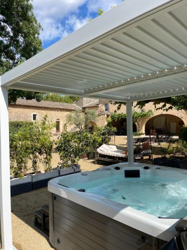a hot tub under a white pergola at Cabane Perchée avec Jacuzzi, au Coeur du Luberon in Oppède