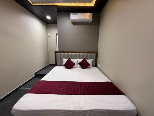 a bedroom with a bed with two red pillows at Hotel Shree Sumedh in Navi Mumbai