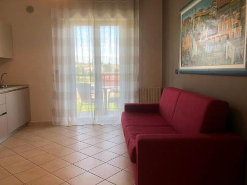 a living room with a red couch in front of a window at Alessio Camere in Bardolino