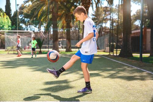 a young boy kicking a soccer ball on a court at Golfo del Sole Hotel & Holiday Resort in Follonica