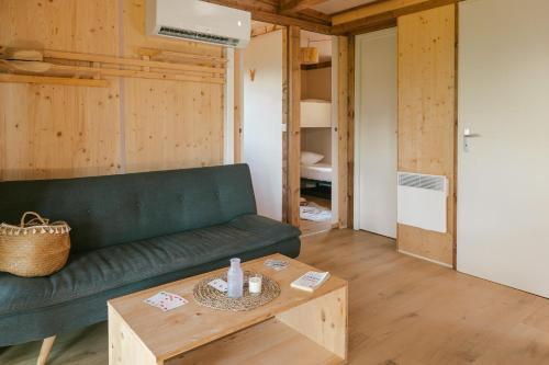 a living room with a green couch and a table at Slow Village Anduze - Cévennes in Corbés
