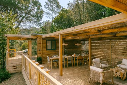 a wooden deck with a table and chairs on it at Slow Village Anduze - Cévennes in Corbés