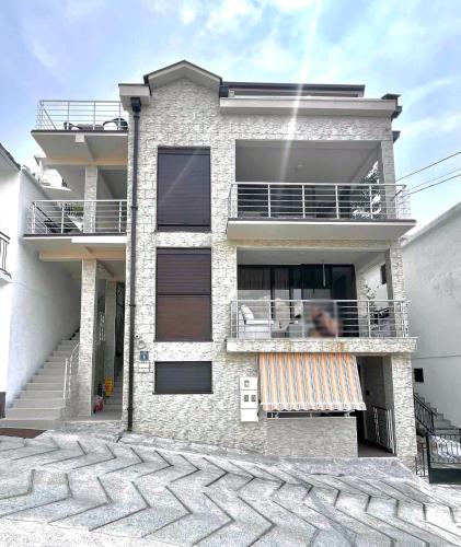 a white brick house with a balcony and stairs at Apartmani Nikic -Tivat in Tivat