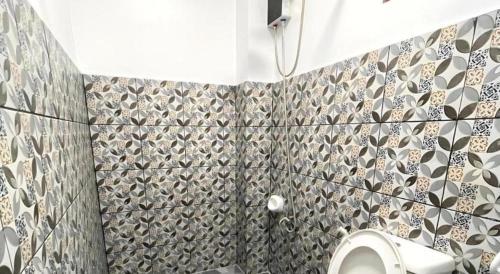 a bathroom with a toilet and a tiled wall at Pilot Hotel in Alaminos