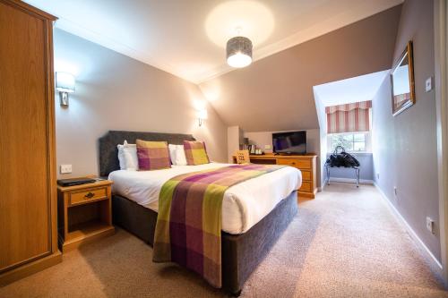 a bedroom with a bed and a desk and a television at Barony Castle Hotel in Peebles