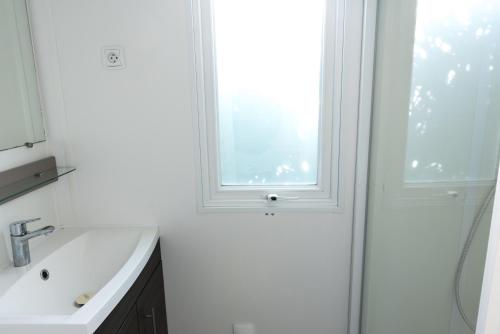 a white bathroom with a sink and a window at Mobile home confort - Fréjus - camping 4 étoiles - in Fréjus