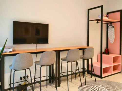 a room with a desk with four chairs and a television at Paxtonz Seasonal Suites in Petaling Jaya