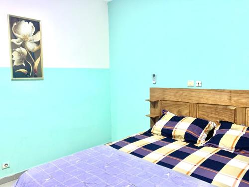 a bedroom with a bed with a blue wall at Porche apart mimboman Yde in Kofa