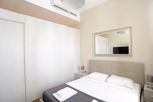 een witte slaapkamer met een bed en een spiegel bij Via Torino Apartment 3 in Milaan