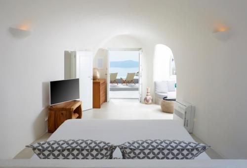 ein weißes Schlafzimmer mit Bett und Fernseher in der Unterkunft Villa Aura in Firostefani