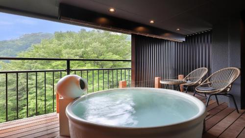 a bath tub on a balcony with a table and chairs at Tsuganoki in Nikko