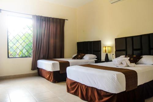Habitación de hotel con 2 camas y ventana en Hotel Hacienda Izamal, en Izamal