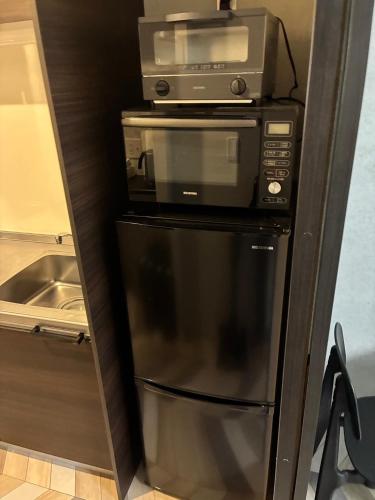 a microwave and a toaster oven on top of a refrigerator at trive kanayama502 - 名駅へアクセス良好 最大5名宿泊可能 in Mutsunochō