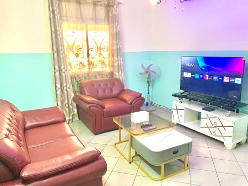 a living room with two leather chairs and a flat screen tv at Luxury apartment Yaoundé in Yaoundé