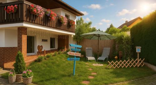 a yard with a house with an umbrella and chairs at SeeOase in Muhr am See inkl Frühstück in Muhr amSee