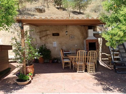 a patio with a table and chairs under a building at Casas Cueva con piscina y barbacoa in Fontanar