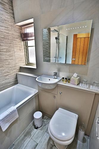 a bathroom with a toilet and a sink and a tub at Cock O' Barton in Coddington