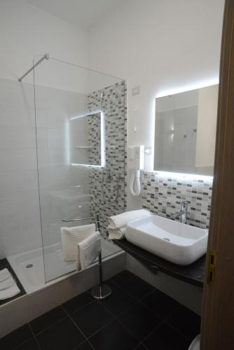 a bathroom with a sink and a glass shower at B&B Napolimilionaria Foria 242 in Naples