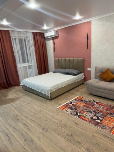 a bedroom with a bed and a couch and a rug at Квартира in Balqash