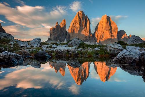 a group of tall rocks with a reflection in the water at Castel Maurn in San Lorenzo di Sebato