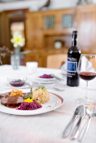 a table with a plate of food and a glass of wine at Café Pension zum Jäger in Buchboden