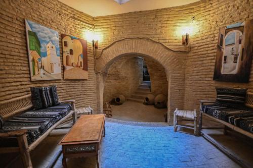 a room with a brick wall with a couch and a table at Palais Harran in Kairouan
