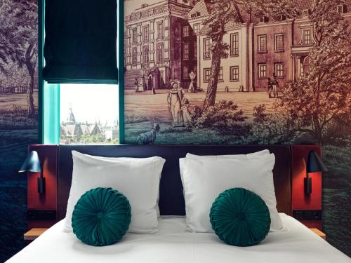 a bedroom with a bed with two green pillows at The Ald Hotel in The Hague