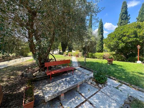 a red bench sitting on a stone path in a park at B&B Villa Miramì in Saturnia