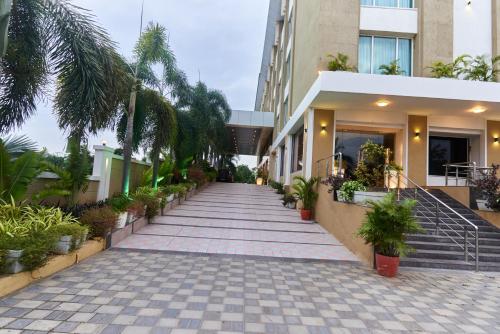 a walkway in front of a building with potted plants at Tania President Inn in Shirdi