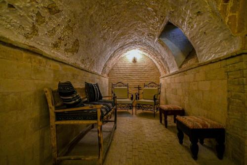 a room with chairs and tables in a stone wall at Palais Harran in Kairouan