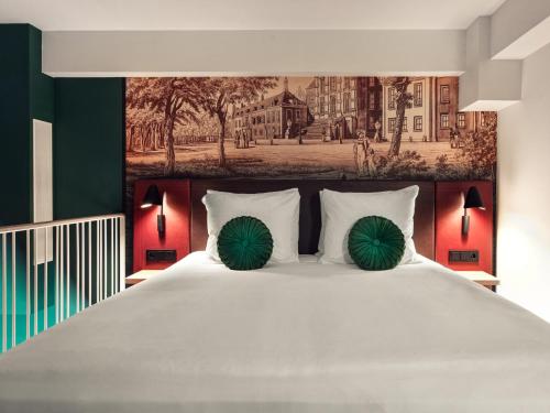 a bedroom with a large white bed with green pillows at The Ald Hotel in The Hague