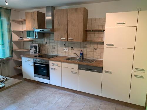 a kitchen with white cabinets and a sink at Ferienwohnung Ödbach mit Terrasse in Konzell