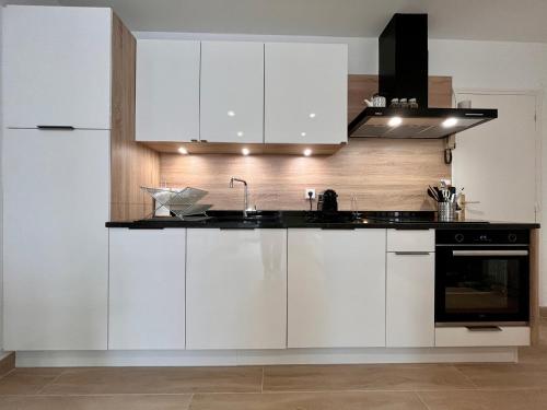 une cuisine avec des armoires blanches et un évier dans l'établissement Appartement lumineux 2 pièces, cœur de Saint-Jean-de-Luz, proche plage et commerces, avec WIFI - FR-1-239-1002, à Saint-Jean-de-Luz