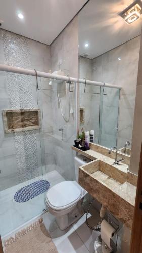 a bathroom with a shower and a toilet and a sink at Flat Esmeralda Juquehy in São Sebastião